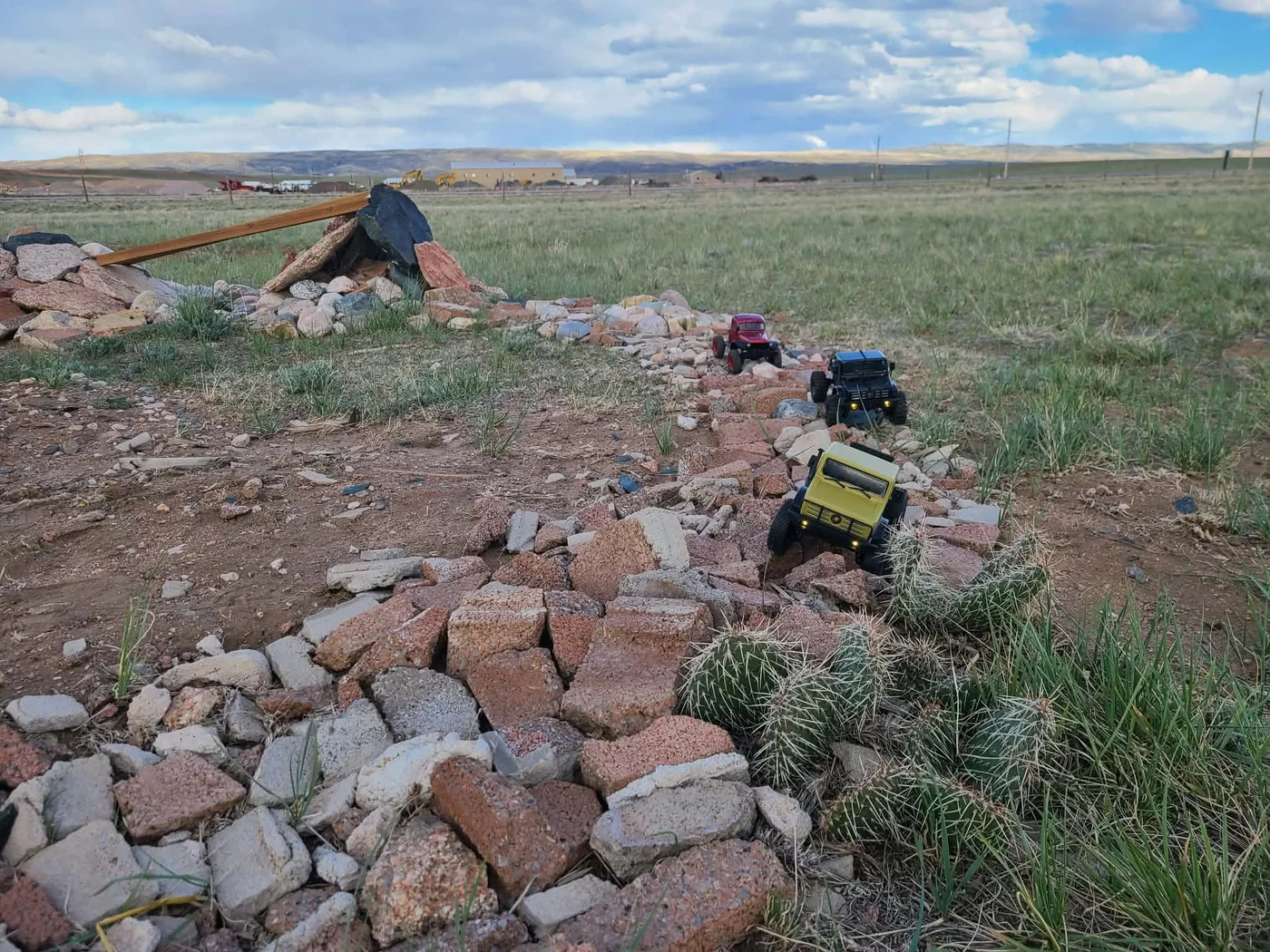 Three RC crawler trucks moving along a rocky trail