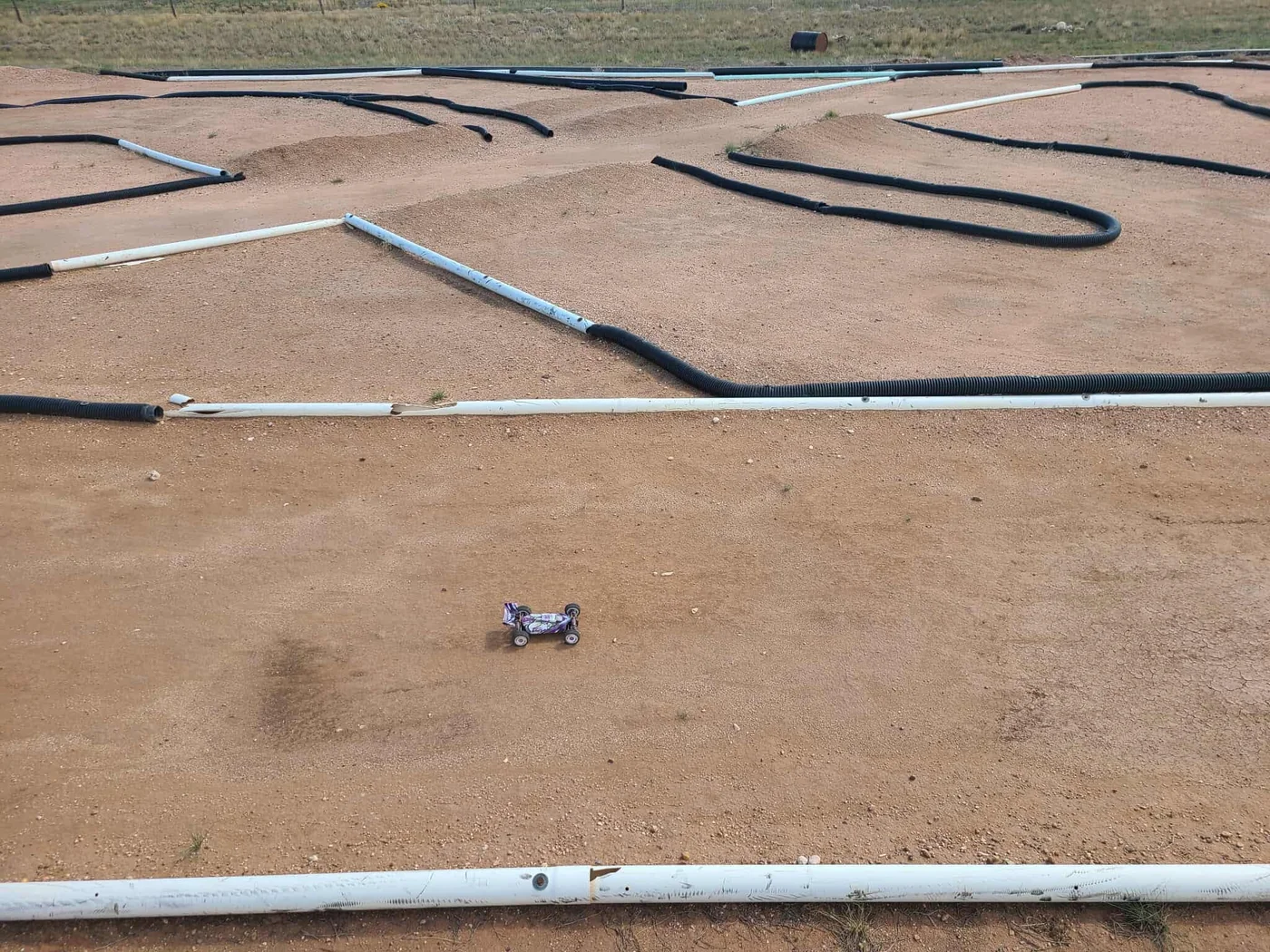 Off-road RC track with dirt lanes and pipe barriers